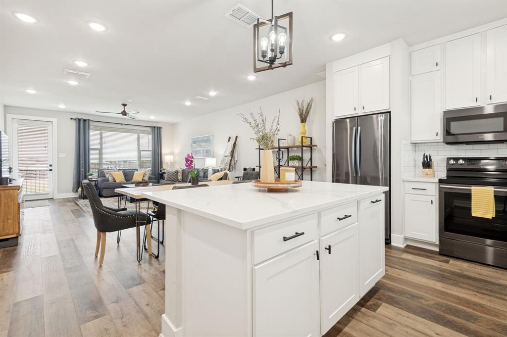 3412 Scenic Point Road, Unit 102 Graford, TX 76449 - Photo 6 of 31 a kitchen with stainless steel appliances kitchen island granite countertop a refrigerator a stove and white cabinets with wooden floor