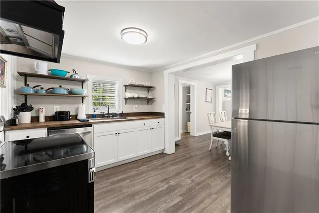 a kitchen with stainless steel appliances a refrigerator a stove a sink and white cabinets with wooden floor