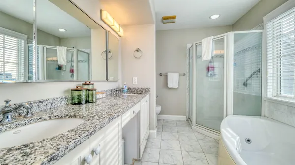 a bathroom with a granite countertop tub sink and mirror