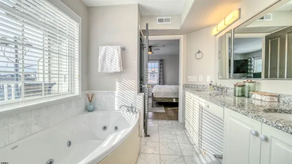 a bathroom with a granite countertop tub sink a mirror and a bathtub