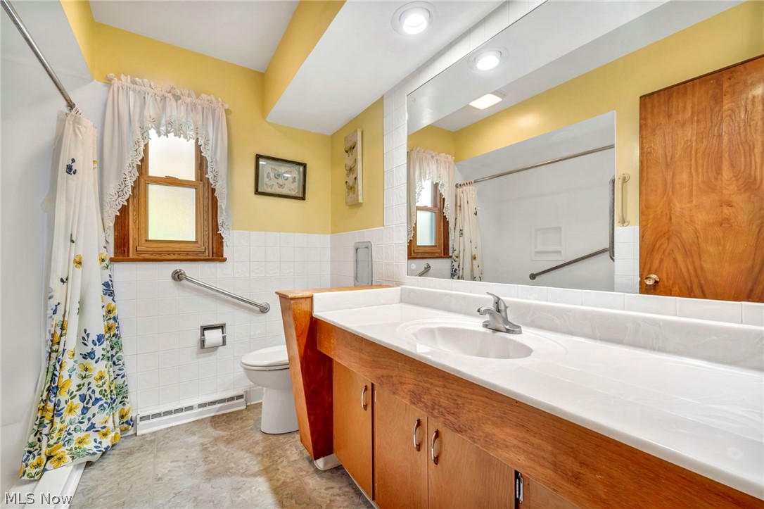 1927 Connect Road Barberton, OH 44203 - Photo 11 of 28 Bathroom featuring tile walls, a healthy amount of sunlight, tile patterned floors, and vanity