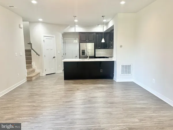 a view of kitchen and empty room with wooden floor