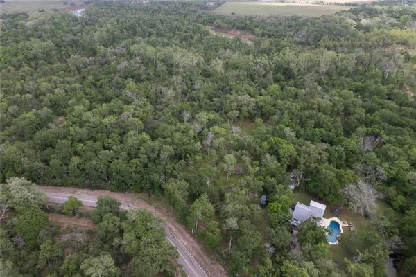an aerial view of residential houses with outdoor space and trees