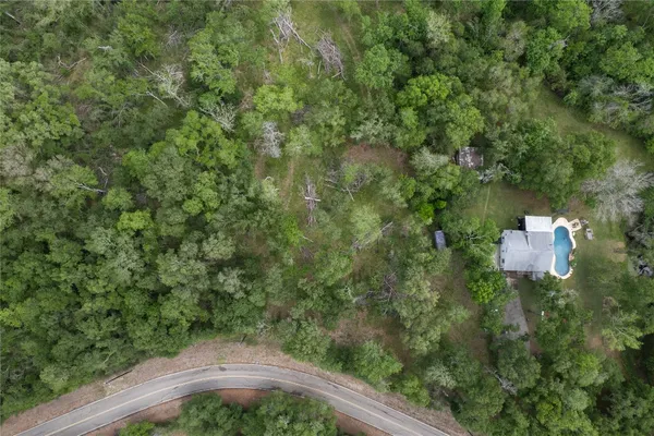 an aerial view of residential house with outdoor space and trees all around