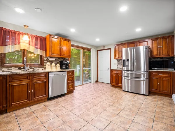 a kitchen with granite countertop a refrigerator and wooden cabinets