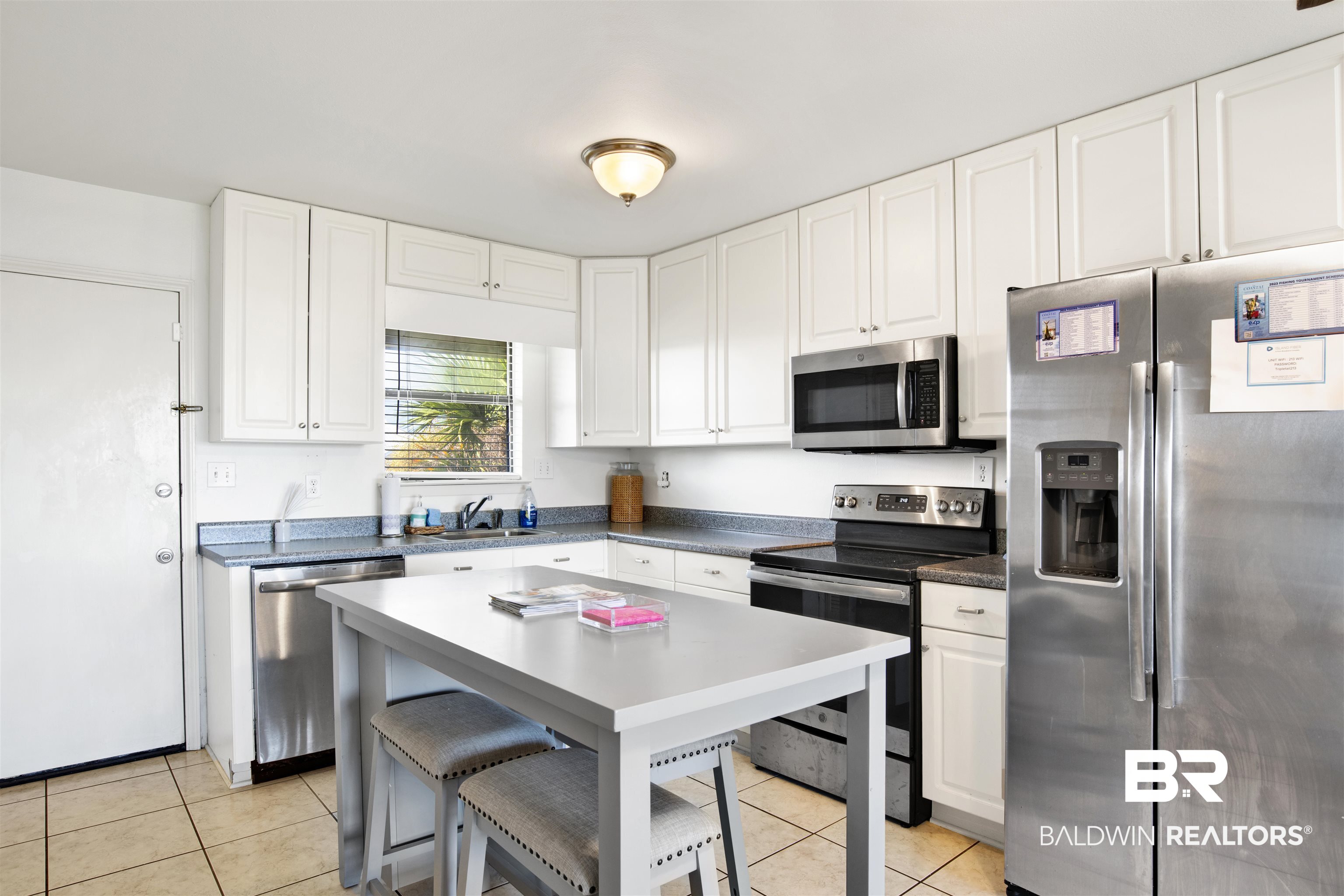 26913 Marina Road, Unit 213 Orange Beach, AL 36561 - Photo 9 of 30 Kitchen featuring white cabinets, appliances with stainless steel finishes, light tile patterned floors, and a breakfast bar area