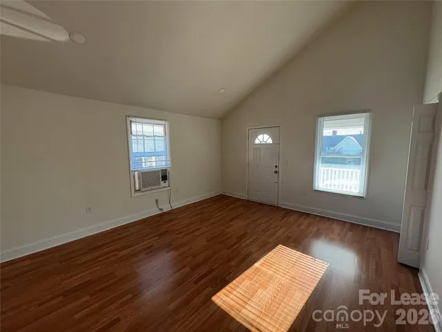 a view of an empty room and window and wooden floor