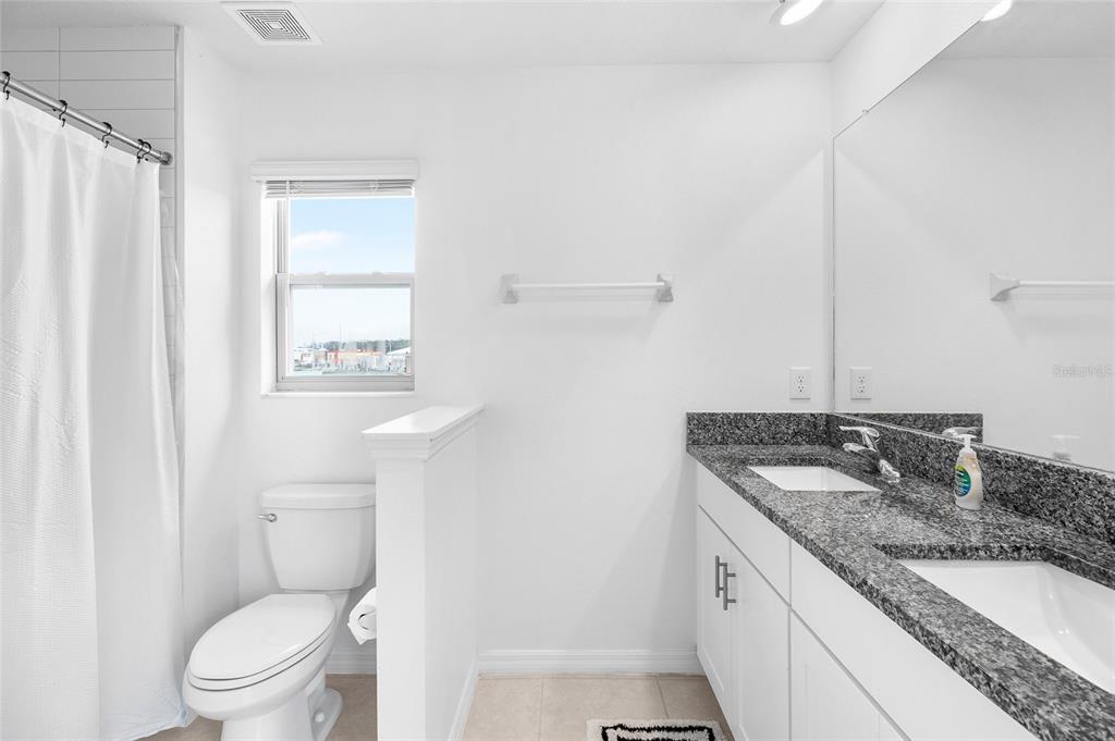 14450 Easy Goer Street Ruskin, FL 33573 - Photo 18 of 27 a bathroom with a granite countertop sink a toilet and a mirror