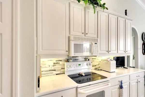 a kitchen with a stove a sink and white cabinets