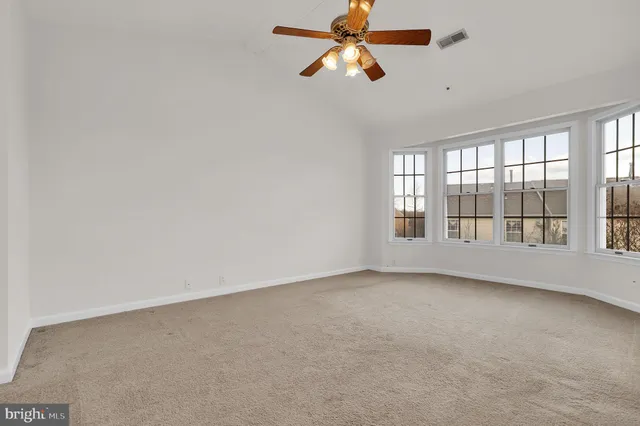 an empty room with chandelier fan and closet area
