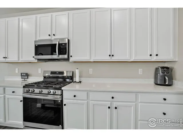a kitchen with stainless steel appliances granite countertop a stove a white cabinet and a granite counter tops