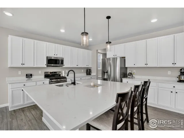 a kitchen with stainless steel appliances a table chairs refrigerator and microwave