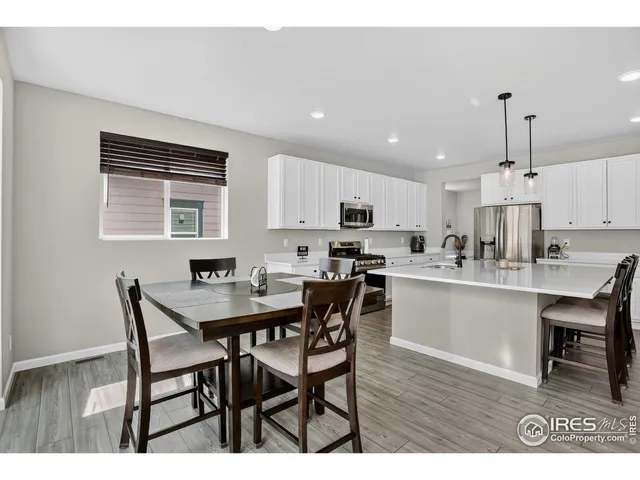a open dining room with kitchen island stainless steel appliances kitchen island granite countertop a dining table chairs and white cabinets