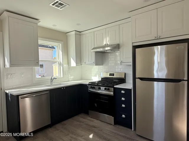 a kitchen with a sink a refrigerator and cabinets