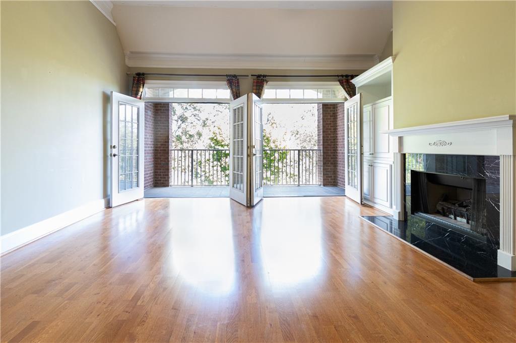 a view of an empty room with wooden floor fireplace and a window