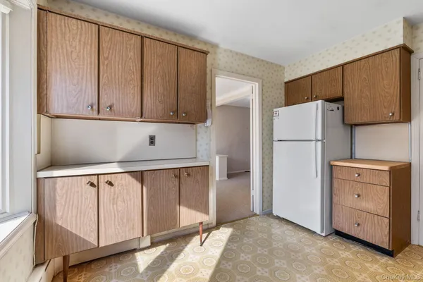 a kitchen with white cabinets and refrigerator