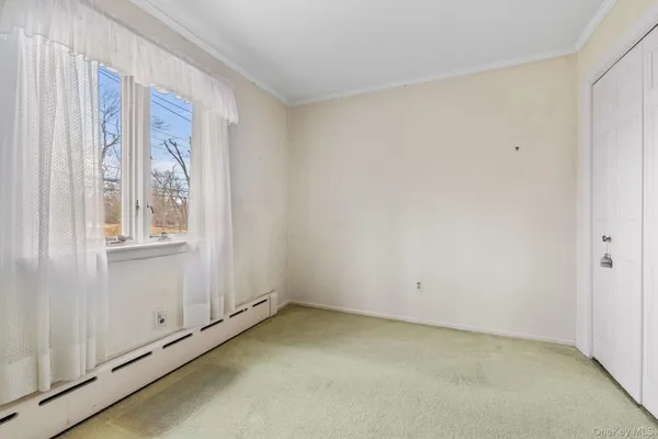 an empty room with a exposed radiator and window