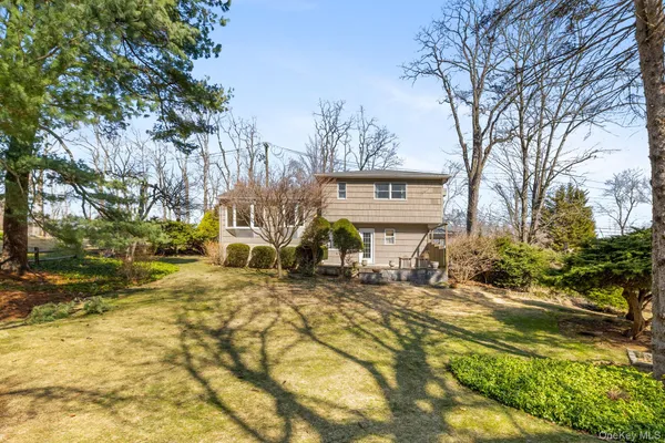 a view of a house with large trees and sitting area