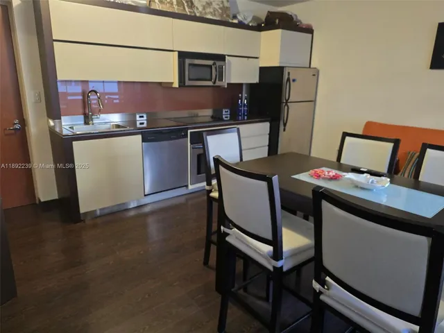 a kitchen with stainless steel appliances granite countertop a stove a refrigerator a microwave and a dining table