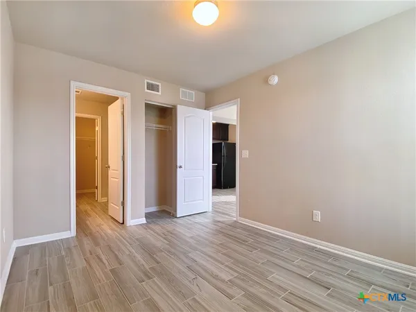 a view of an empty room with wooden floor and closet