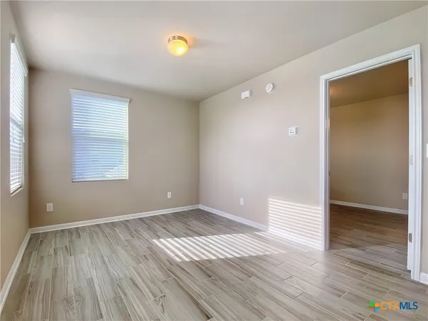 an empty room with wooden floor and windows