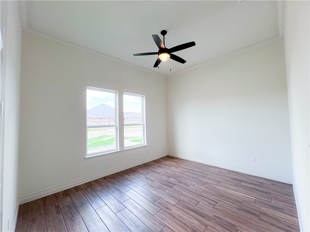 6918 Pacific Way Corpus Christi, TX 78414 - Photo 20 of 34 an empty room with wooden floor a ceiling fan and windows