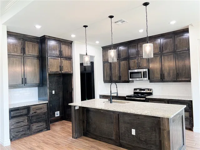 a kitchen with stainless steel appliances kitchen island granite countertop a refrigerator and a sink