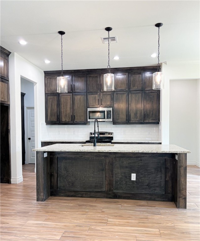 6918 Pacific Way Corpus Christi, TX 78414 - Photo 5 of 34 a kitchen with stainless steel appliances granite countertop a sink a stove and a wooden floor