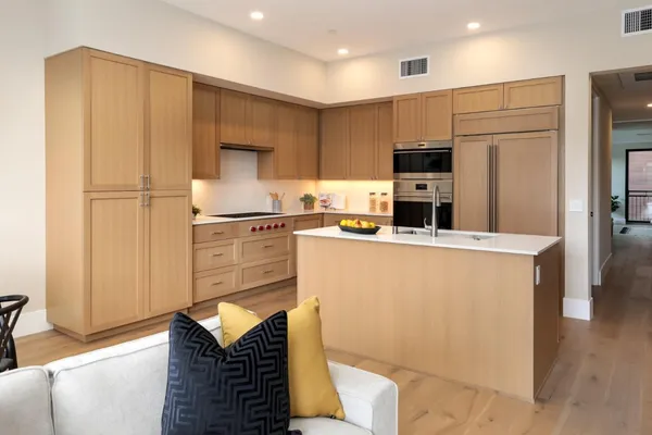 a kitchen with stainless steel appliances granite countertop a refrigerator a stove and a sink with wooden floor