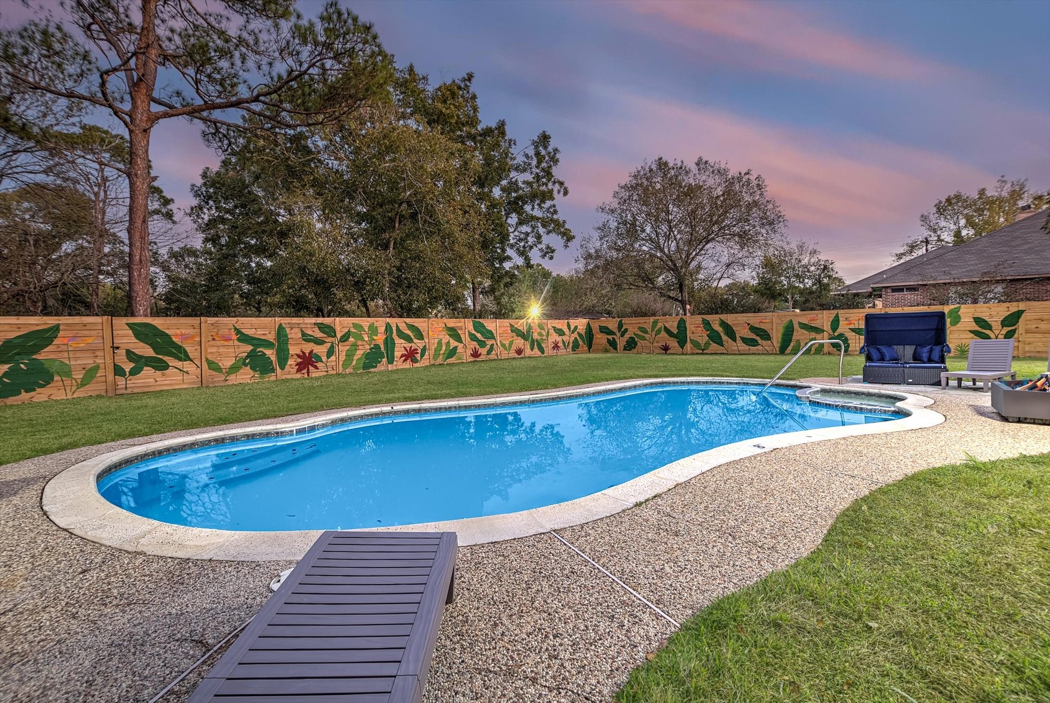 a view of swimming pool with a yard and trees in the background