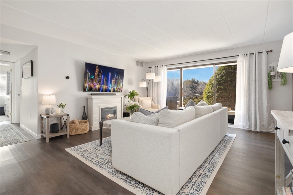 a living room with fireplace furniture and a large window