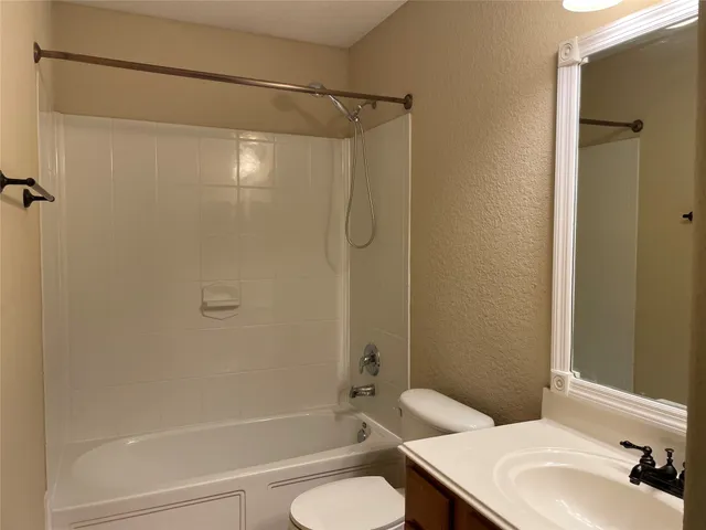 a bathroom with a granite countertop bathtub shower sink vanity and toilet