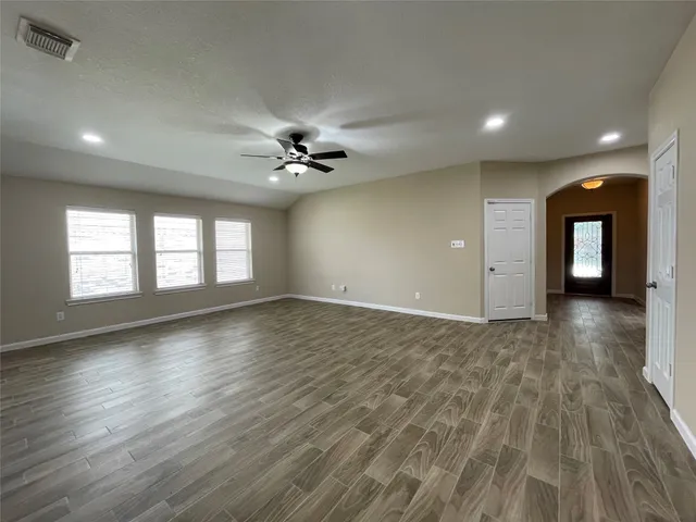 a view of an empty room with glass door and wooden floor