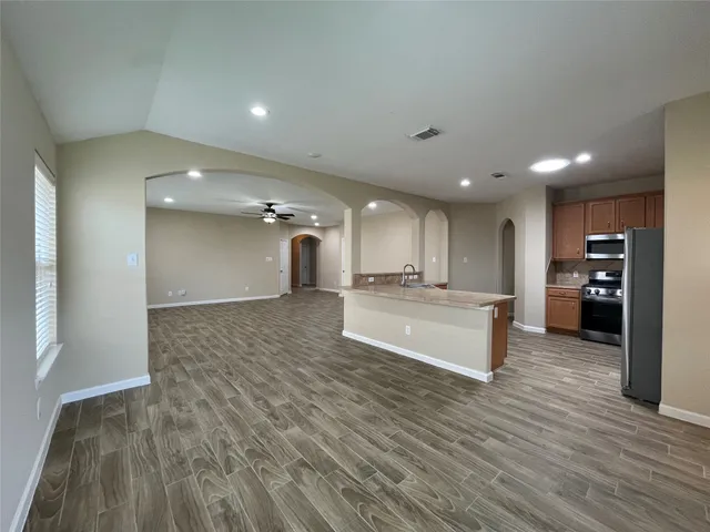 a view of kitchen with kitchen island a sink wooden floor and a refrigerator