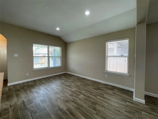 an empty room with wooden floor and windows