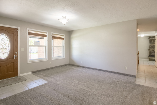 634 South 2100th Street West Vernal, UT 84078 - Photo 9 of 71 Entry space featuring a wood-finish door with an oval leaded glass insert, two windows with blinds, a ceiling-mounted light fixture, and textured gray carpet with a tiled entryway