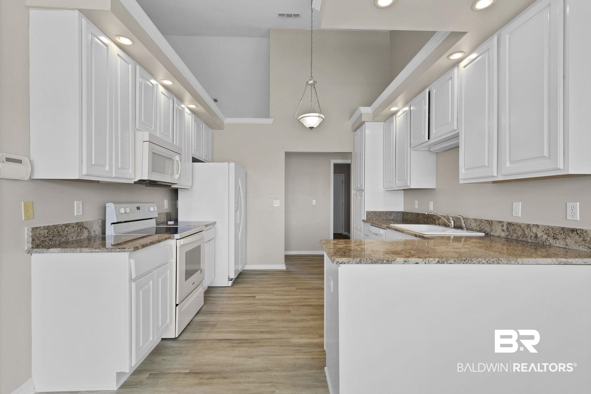 10238 Grove Drive Fairhope, AL 36532 - Photo 10 of 39 Kitchen featuring a peninsula, white appliances, a sink, white cabinetry, and hanging light fixtures