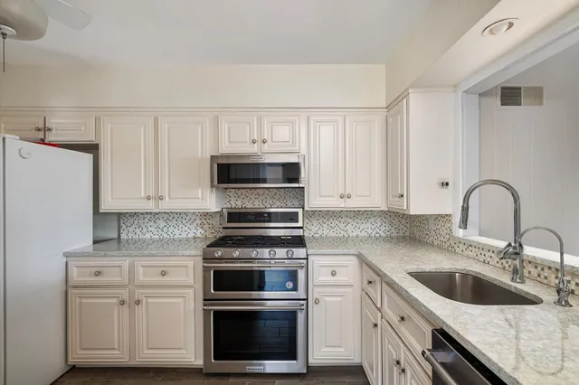 a kitchen with white cabinets sink and stainless steel appliances
