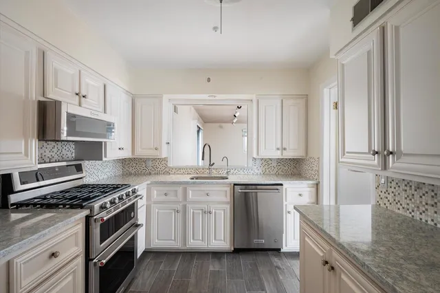 a kitchen with stainless steel appliances granite countertop a stove top oven a sink and dishwasher with wooden floor