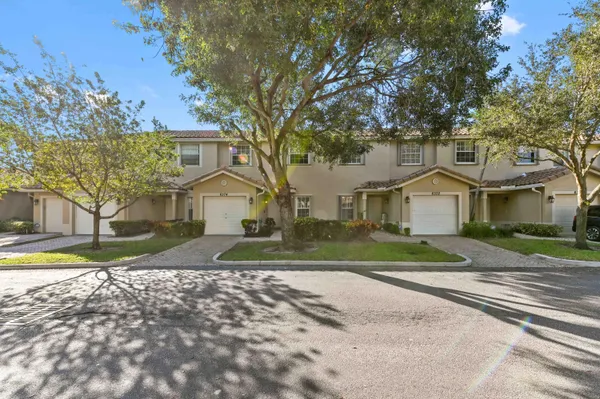 a front view of a house with a yard and large trees