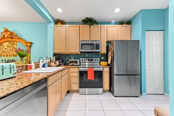 a kitchen with stainless steel appliances granite countertop a refrigerator and a stove top oven