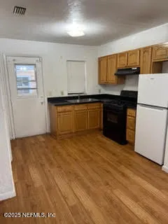 a kitchen with granite countertop a refrigerator and a stove top oven