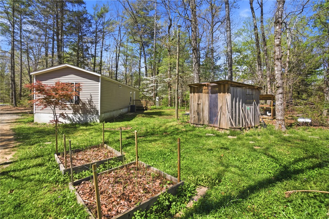 289 Bauknight Road Mountain Rest, SC 29664 - Photo 36 of 36 This tranquil property features a modest home nestled among trees, with raised garden beds and a small shed.