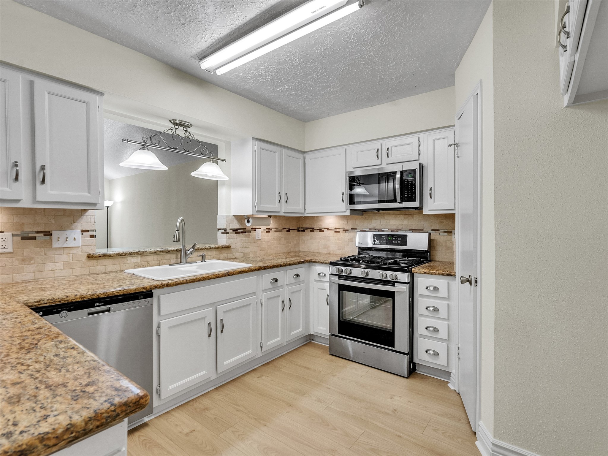 32 Sarita Road Angleton, TX 77515 - Photo 14 of 25 a kitchen with granite countertop a stove sink and microwave