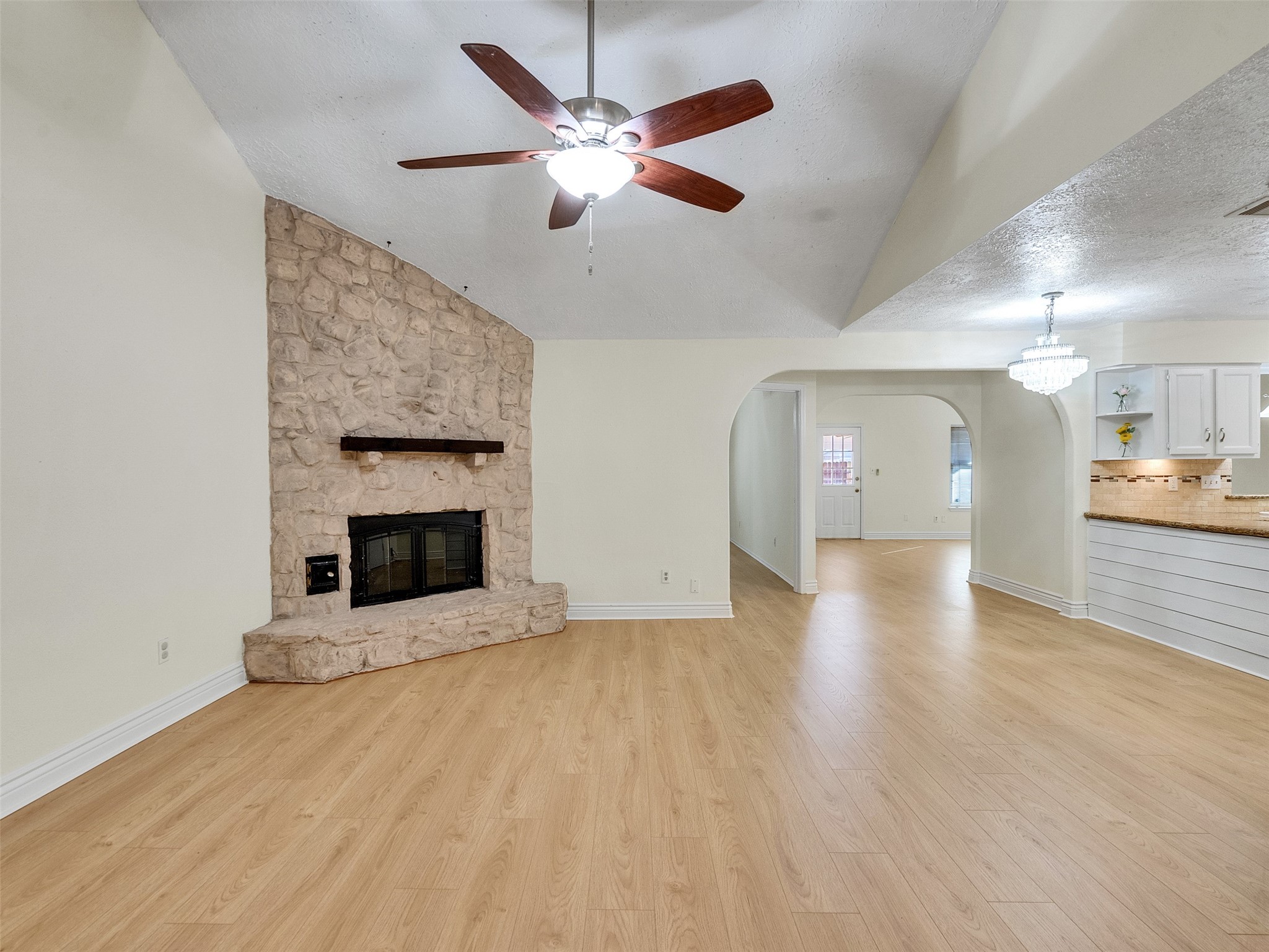 32 Sarita Road Angleton, TX 77515 - Photo 3 of 25 an empty room with wooden floor a ceiling fan a fireplace and windows