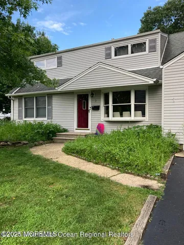 a view of a white house with a yard and potted plants