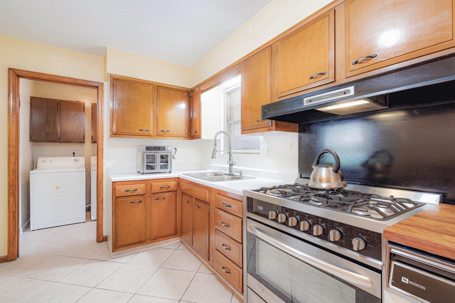 5040 Warrington Road Memphis, TN 38118 - Photo 18 of 29 Kitchen featuring stainless steel gas range oven, washer / clothes dryer, under cabinet range hood, a sink, and light countertops