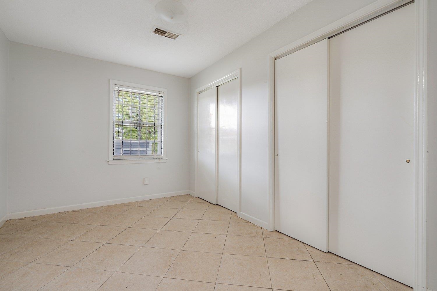 5040 Warrington Road Memphis, TN 38118 - Photo 23 of 29 Unfurnished bedroom featuring multiple closets, baseboards, light tile patterned floors, and visible vents
