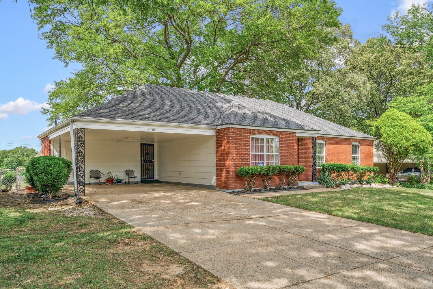 5040 Warrington Road Memphis, TN 38118 - Photo 3 of 29 Ranch-style house featuring brick siding, concrete driveway, a front yard, an attached carport, and roof with shingles
