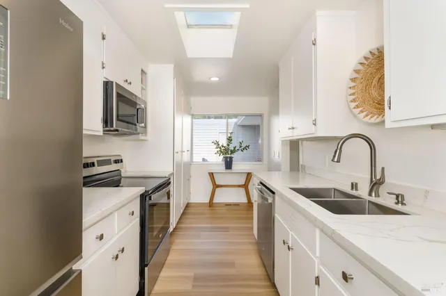 a kitchen with stainless steel appliances granite countertop a sink and a stove top oven with wooden floor